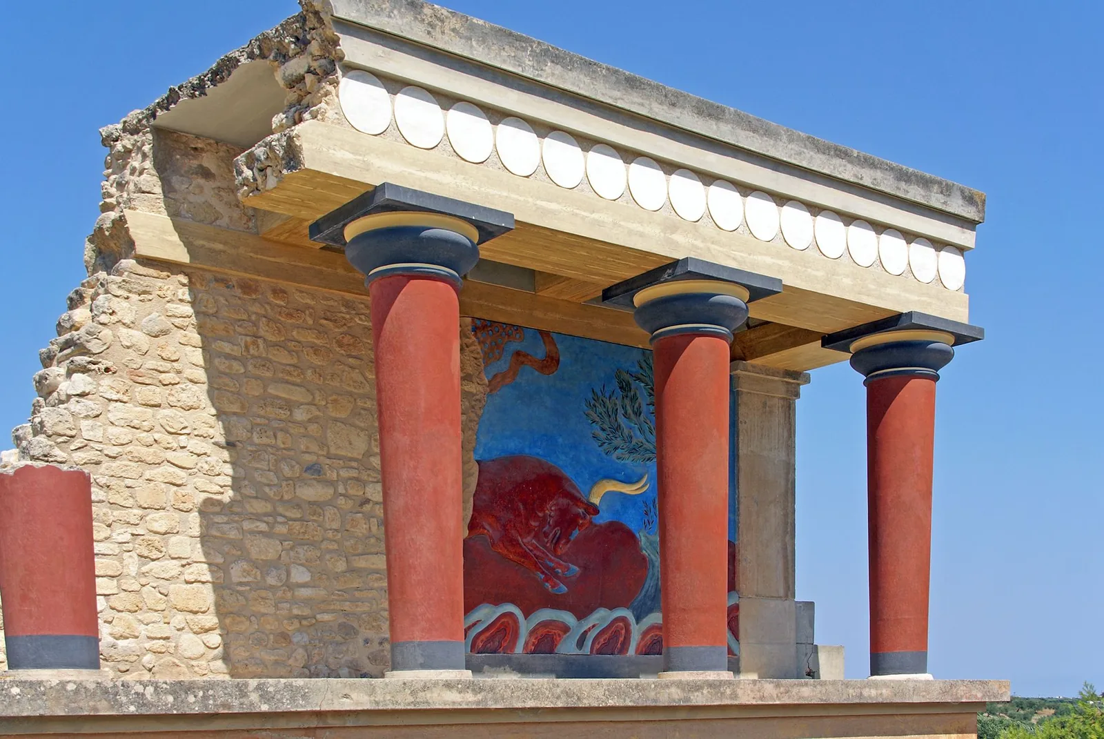 Reconstructed red columns and a copied fresco at the Palace of Knossos, the work of Arthur Evans.