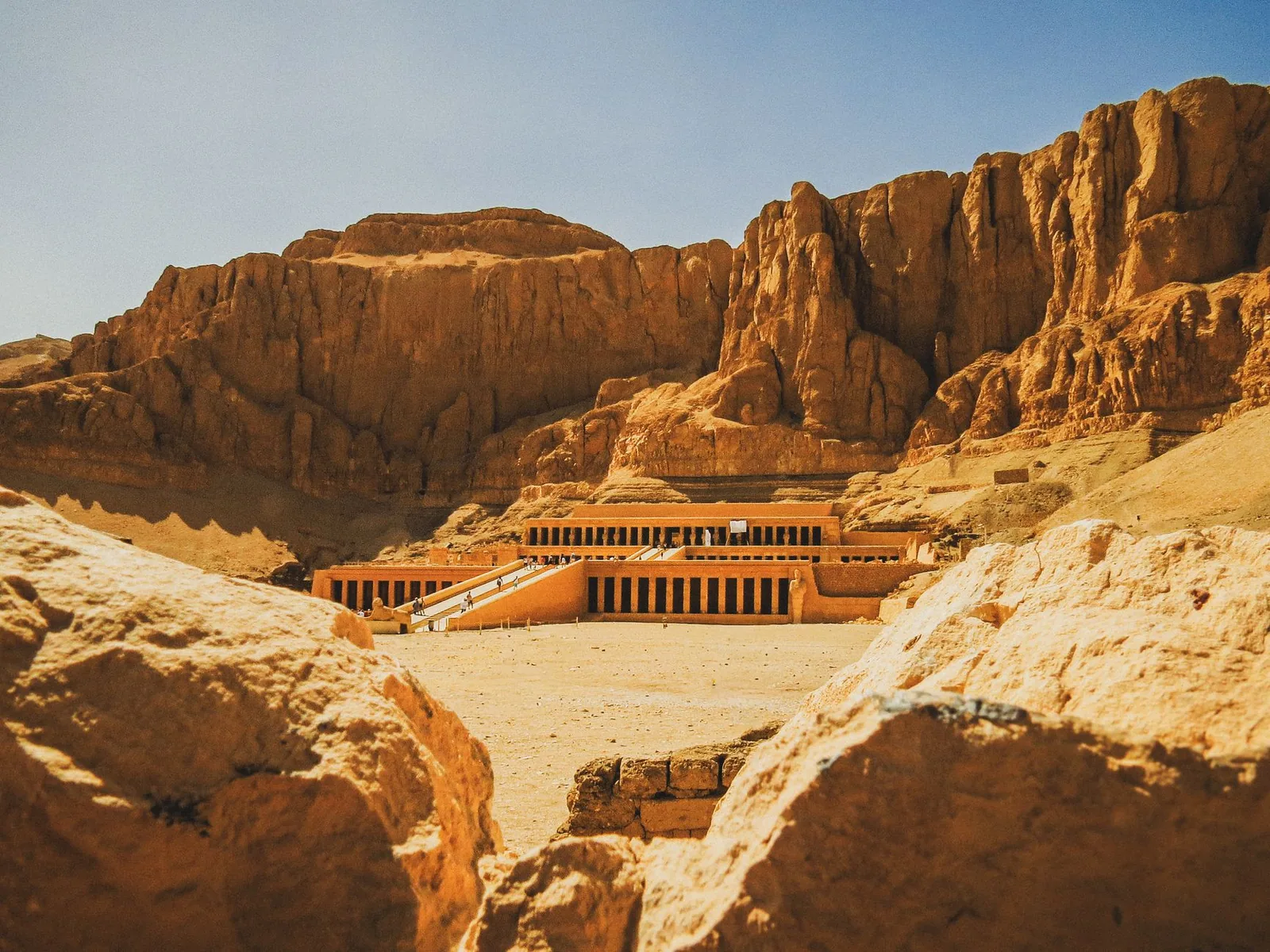The terraced colonnades of Hatshepsut's mortuary temple at Deir el-Bahari, set against the towering limestone cliffs of the Luxor west bank.