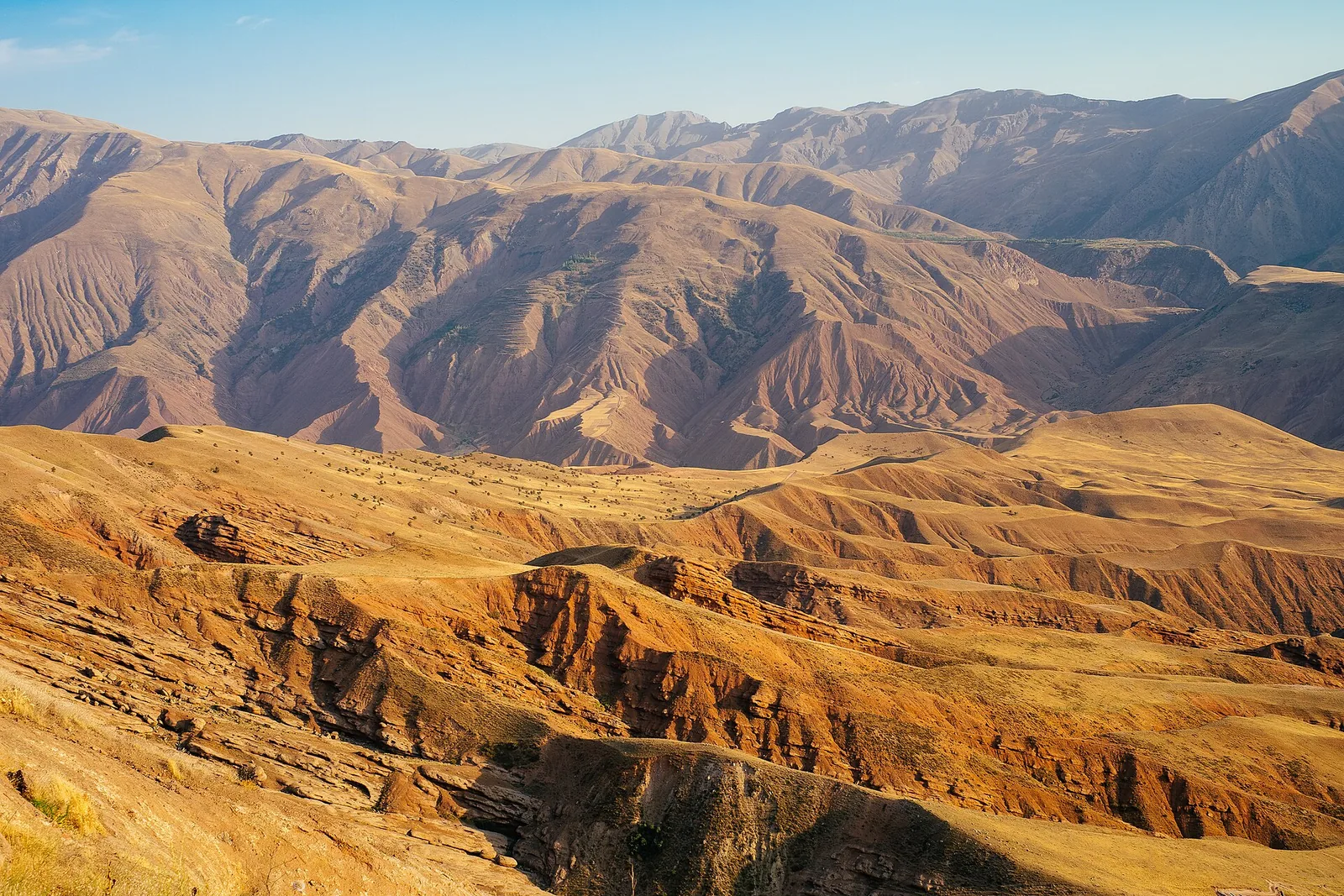 Bare ochre ridges and deep valleys of the Alborz range seen from the rock of Alamut Castle in Qazvin province, Iran.